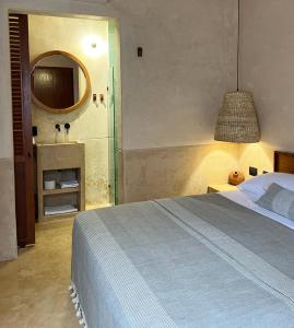 a bedroom with a bed and a bathroom with a mirror at Bajo las Hojas in Campeche