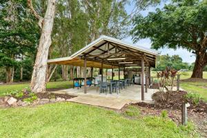 einen Pavillon mit Tischen und Stühlen in einem Park in der Unterkunft Bali Hai Child Free Holiday Park Mission Beach in Mission Beach