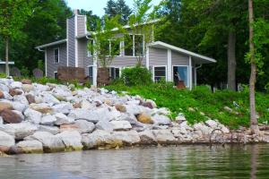 a house with a bunch of rocks next to the water at Shelburne Bay Stay & Play in South Burlington