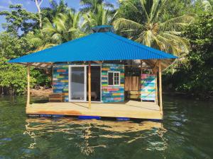 a small house with a blue roof on the water at El Toucan Loco floating lodge in Tierra Oscura
