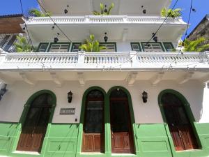 a white building with green doors and a balcony at AmazINN Places Private Rooftop and Jacuzzi IX in Panama City