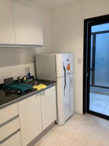 a kitchen with a white refrigerator and a window at Hermoso departamento boutique con pileta in Salta