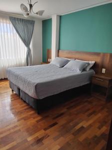 a bedroom with a bed and a blue wall at Hotel Esmeralda in La Paz