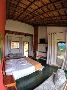 a bedroom with a large bed and two windows at Pousada Mirante Serra Verde in Carrancas