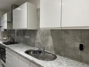 uma cozinha com um lavatório e armários brancos em BEAUTIFUL ROOMS ONLY FEW STEPS AWAY FROM BRUCE GROVE TOTTENHAM STADIUM em Londres
