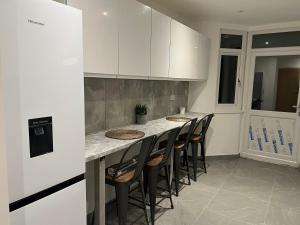 a kitchen with a counter with chairs around it at BEAUTIFUL ROOMS ONLY FEW STEPS AWAY FROM BRUCE GROVE TOTTENHAM STADIUM in London