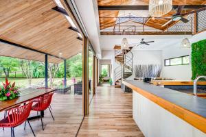 una cucina a pianta aperta e una sala da pranzo con sedie rosse e soffitti in legno di La Casa Tico Tango a Playa Grande