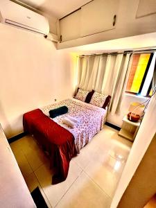 a bedroom with a bed with a red blanket and a window at Flat perfeito no coração de Boa Viagem in Recife