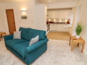 a living room with a blue couch and a kitchen at Bronte House in Carnforth