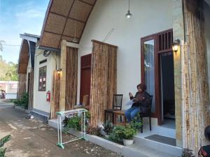 a woman sitting on a porch of a house at Sulis homestay in Kuta Lombok