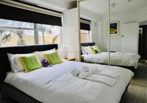 a bedroom with two beds with towels and a mirror at Spectacular Views of Sydney Harbour with Free Parking in Sydney