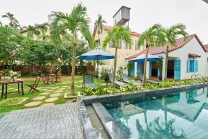 a swimming pool with chairs and umbrellas next to a building at Legend Oasis Hoi An Boutique Hotel in Hoi An