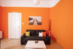 sala de estar con sofá negro y pared de color naranja en City Centre Apartment with 3 Bathrooms, en Budapest