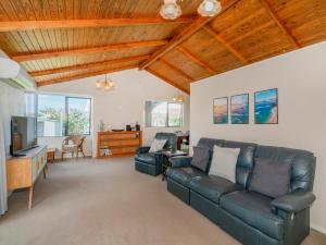 a living room with a couch and a tv at Treasure on Chestnut - Tairua Holiday Home in Tairua