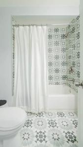 a bathroom with a white shower curtain and a toilet at King bed open floorplan in heart of Bham in Birmingham