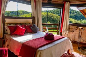 a bedroom with a bed with a large window at Pousada Chalé Sol Nascente in Santo Antônio do Pinhal