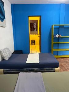 a blue room with a bed and a yellow door at Casa Makoi in Tamanique