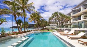 a pool at a resort with palm trees and the ocean at Fairshore Apartment 15, Noosa Heads in Noosa Heads