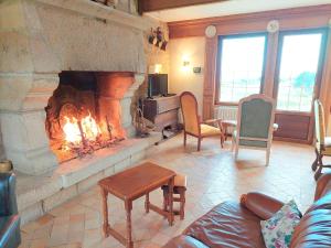ein Wohnzimmer mit einem Kamin mit Stühlen und einem Sofa in der Unterkunft Breton granite stone house with fantastic sea views in Saint-Pol-de-Léon
