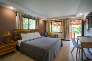 1 dormitorio con 1 cama, escritorio y ventanas en Hotel Arco Iris en Tamarindo