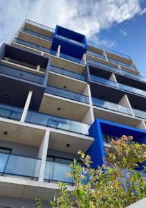 un edificio de apartamentos con ventanas azules y árboles en Depto premium frente al mar, cochera y piscina!! en Mar del Plata