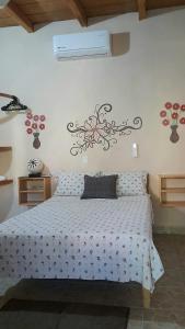 1 dormitorio con 1 cama con diseño floral en la pared en Casa Aldairis, en Mazunte