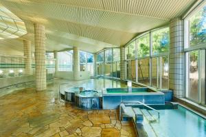 - une piscine intérieure dans un bâtiment avec fenêtres dans l'établissement KAMENOI HOTEL Kitsuregawa, à Sakura