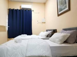 two beds in a room with a blue curtain at UIA Younee Kuantan Homestay 3R2B 9pax 5 min to town in Kuantan