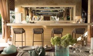 un bar con taburetes y una mesa con platos y vasos en Villa Alu Lima, en Seminyak