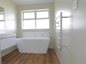 a white bathroom with a bath tub and a window at Fiordland Getaway - Te Anau Holiday Home in Te Anau +17 photos
