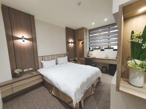 um quarto com uma grande cama branca e uma janela em Grace Hotel Dunbei em Taipei