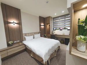 una camera da letto con un grande letto bianco e una finestra di Grace Hotel Dunbei a Taipei