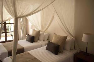 a bedroom with two beds with curtains and a window at Villa Alu Lima in Seminyak