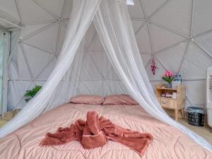 a bed with a canopy with two towels on it at Dome บ้านสกายพฤกษ์ in Mon Jam