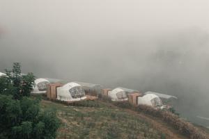 a group of domes on a hill in the fog at Dome บ้านสกายพฤกษ์ in Mon Jam