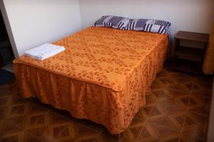 ein Bett mit orangefarbener Tagesdecke in einem Zimmer in der Unterkunft Hinkiori Inn - Hotel Manu in Pillcopata