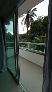 uma varanda com uma porta de vidro deslizante e uma palmeira em Apartamento Maresia em Morro de São Paulo