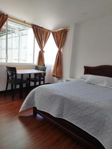 a bedroom with a bed and a table and a window at Habitaciones Alkimya in Loja