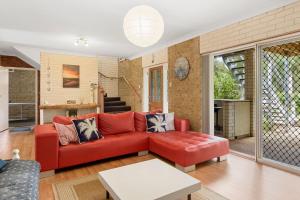 a living room with a red couch and a table at Broadbeach Retreat 32 Broadbeach Drive in Carrickalinga