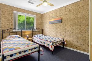 two beds in a room with brick walls at Broadbeach Retreat 32 Broadbeach Drive in Carrickalinga