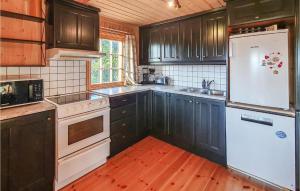 cocina con armarios negros y nevera blanca en 3 Bedroom Awesome Home In Svingvoll, en Svingvoll