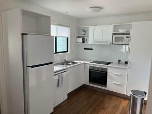 a white kitchen with a refrigerator and a sink at Noosa Lakes Resort in Noosaville