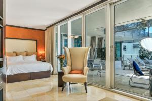 1 dormitorio con 1 cama, 1 silla y balcón en Boutique Suites 3 min walk to beach, en Miami Beach