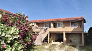 une maison avec un garage et quelques fleurs roses dans l'établissement Apartments Remi - 300m from sea, à Nin