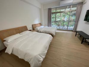 two beds in a room with a large window at 畔山民宿 in Zhonghe