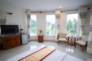 a bedroom with a bed and a tv and some windows at Khách Sạn Bông Sen in Vị Thanh