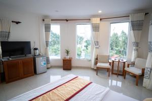 a bedroom with a bed and a tv and some windows at Khách Sạn Bông Sen in Vị Thanh