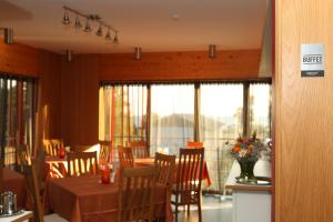 a dining room with a table and chairs and windows at Dirhami Guesthouse in Dirhami