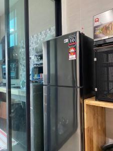 a stainless steel refrigerator in a kitchen next to a microwave at TERATAK QASEH Meru in Kapar