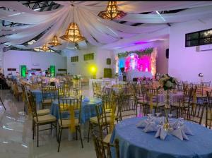 un salón de banquetes con mesas y sillas azules y un escenario en RedDoorz Covelandia Garden Resort Nueva Ecija, 